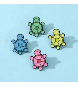 Detailed view of four colorful turtle enamel pins in green, blue, yellow and pink shades
