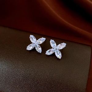 Macro view of silver flower stud earrings with marquise-cut zircons on leather texture
