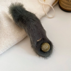 Close-up of gray plush hair clip with marble bead detail and metallic clamp base