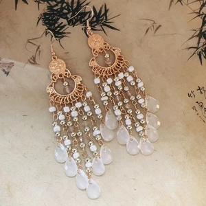 Macro detail of Bohemian tassel earrings with white beads and water drop pendants