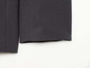 Detailed close-up of dark grey suit trousers cuff featuring clean stitching and fine fabric