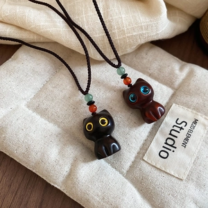 Close-up of handmade wooden cat pendants with colorful beads and black woven cord
