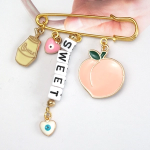 Detail of gold safety pin brooch with Milk bottle, Sweet beads, and Peach charms
