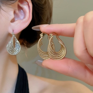 Macro detail of layered twist oval earrings in gold and silver finish on model