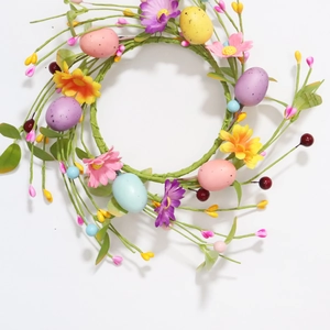 Close-up of Easter egg wreath with pink silk bows and colorful daisies on white background