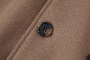 Macro detail of dark marble button and camel wool fabric texture on long coat