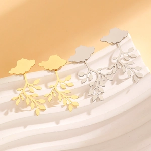Elegant 3D leaf drop earrings in gold and silver finish on artistic white display