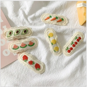 Detailed close-up of colorful embroidered fruit hair clips featuring strawberry and lemon