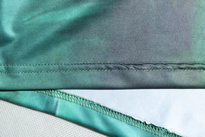 Detailed view of the gradient green dress hem featuring professional stitching and flat seams