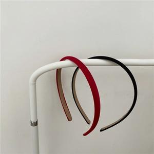 Minimalist fabric headband in red and black matte finish on a modern white display stand