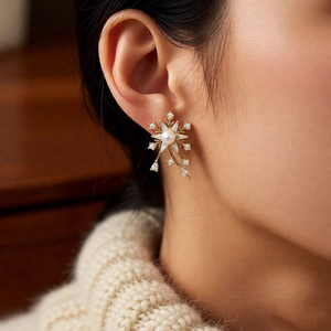 Vue macro de boucles d'oreilles flocon en perles et zircons avec finition dorée