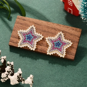 Close-up of colorful star earrings with pavé zircons on a rustic wooden base