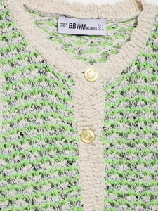 Close-up of textured knit cardigan with embossed metal lion buttons and collar detail