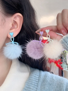 Close-up of soft faux fur pompom earrings with heart studs and bow details for women