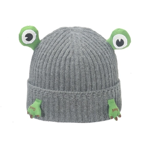 Detail of grey ribbed beanie with green 3D frog eyes and 'Good' embroidered claws
