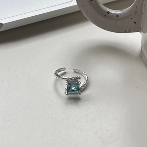 Irregular S925 sterling silver open ring with blue square gemstone on a workspace
