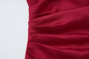 Detail shot of the side ruching on a wine red satin dress with elegant silky texture