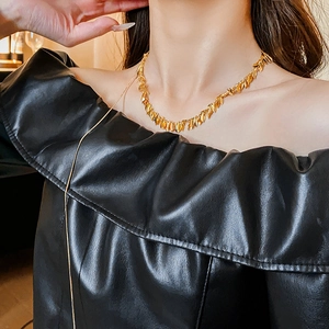 Detail of gold leaf fringe necklace and long layered chain on a black dress
