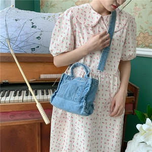 Retro washed denim shoulder bag styled with broad strap in a vintage aesthetic room