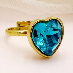Gros plan d'une bague dorée en acier inoxydable avec un zircon bleu en forme de cœur
