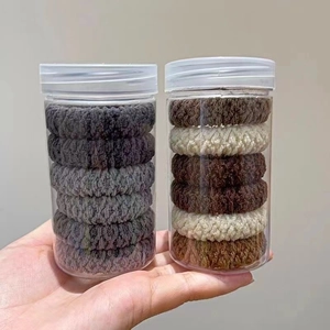 Macro shot of high-elasticity braided hair ties set in clear jars with Morandi tones