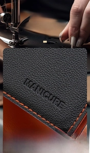 Detail of premium black leather manicure set case with orange stitching and embossed text