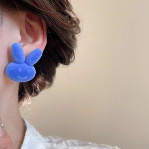 Detailed close-up of a blue flocked bunny earring worn by a model in a luxury style