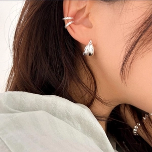 Close-up of silver textured water-drop earrings and ribbed ear cuffs on a model