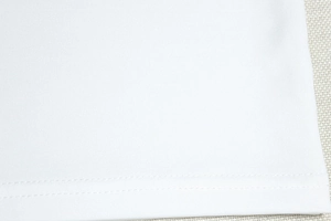 Close-up of white dress hem showing high-quality double-needle stitching and fabric texture