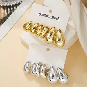 Macro detail of tear-shaped metal stud earrings set in gold and silver finish
