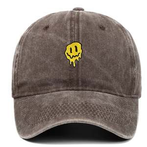 Détail de la broderie smiley jaune sur une casquette de baseball en coton marron délavé