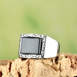 Détail d'une bague en acier argenté avec pierre noire et gravures sur les côtés