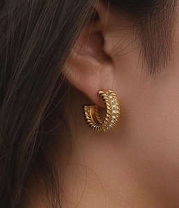 Detailed close-up of 18K gold-plated C-shaped twisted earrings with white cubic zirconia