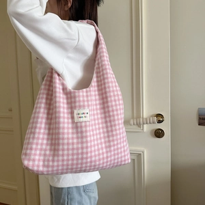 Modell mit rosa karierter Canvas-Einkaufstasche und Stoffetikett im Wohnbereich