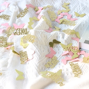 Mix of pink and gold butterfly confetti with Happy Birthday letter shapes on a blanket