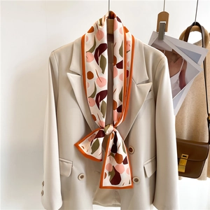 Foulard étroit en soie imprimé noué sur un blazer crème pour un style élégant