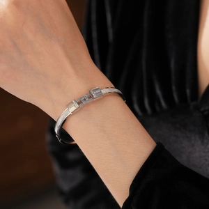 Detailed view of silver titanium steel T-shaped bangle with cubic zirconia on a model