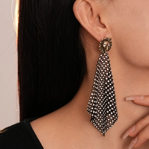 Close-up of a model wearing gold lion head earrings with sparkling rhinestone mesh fringe