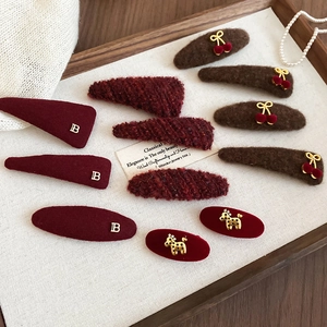 Detailed close-up of plush velvet and tweed triangle hair clips in deep burgundy tones