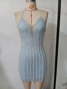 Détail de robe en mesh bleu clair ornée de perles blanches et strass avec coupe moulante