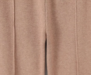 Detail of camel knitted trousers showing vertical seam stitching and premium wool texture