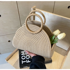 Detail of a beige woven beach bag with round handles and decorative white tulips