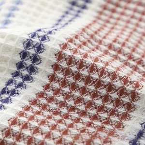 Macro shot of breathable waffle weave cotton towel with blue and red striped texture