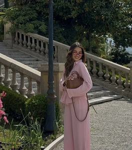 Detail of pink long-sleeved shirt and wide-leg trousers set with elegant draping fabric