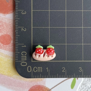 Detailed view of mini resin strawberry bread charm on a ruler showing 1.5cm width