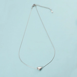 Minimalist silver stainless steel heart pendant necklace on a light blue background