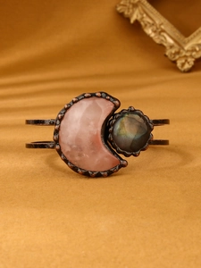 Detailed shot of vintage bronze cuff bracelet with moon-shaped rose quartz and labradorite