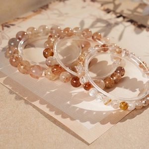 Natural red rutilated quartz beaded bracelets on a minimalist textured display