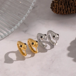 Schlangen-Ohrringe in Gold und Silber mit Kristallaugen auf einem Marmorhintergrund