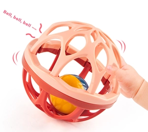 Close-up of a baby's hand grasping a colorful soft silicone rattle ball with bell sound